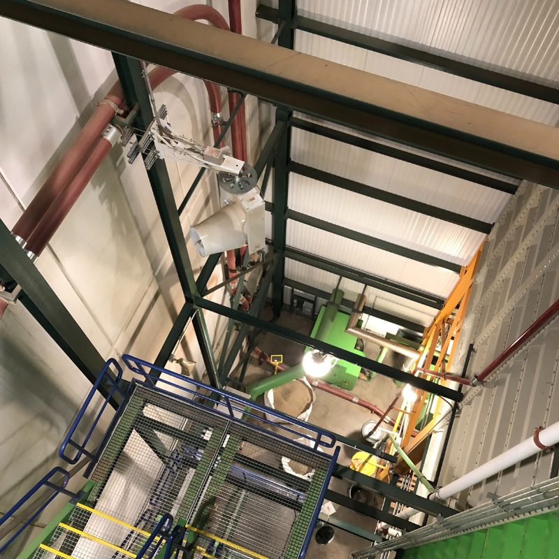 Warehouse stairwell with mounted industrial fan improving air quality and circulation.